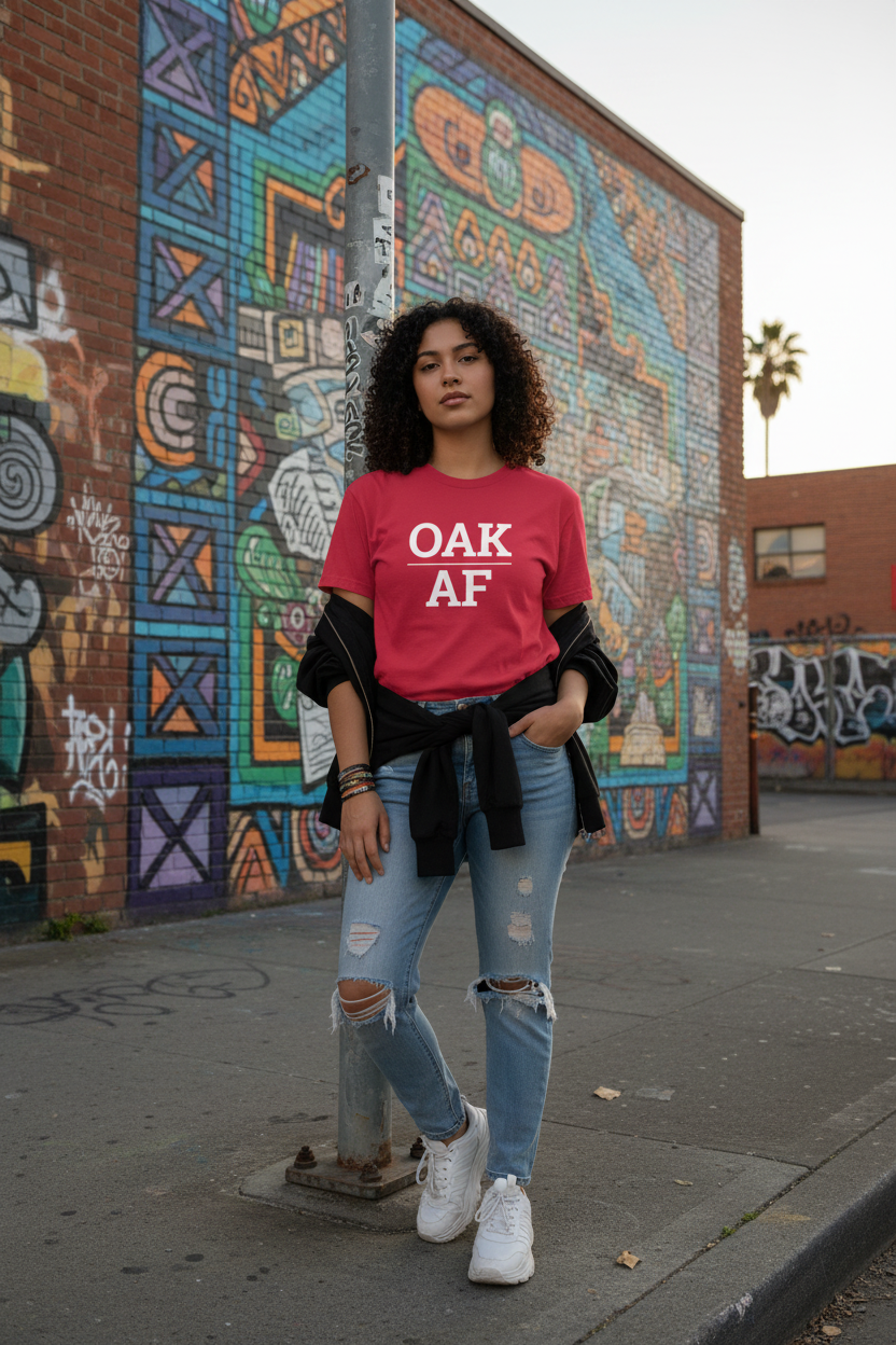 Model wearing OAK_AF cardinal red tee at Fruitvale Village murals, Oakland, CA